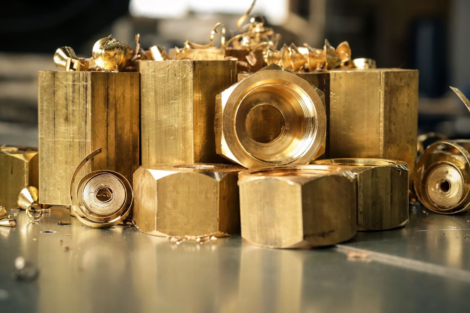 A collection of brass bars, nuts, and shavings on a metal surface.
